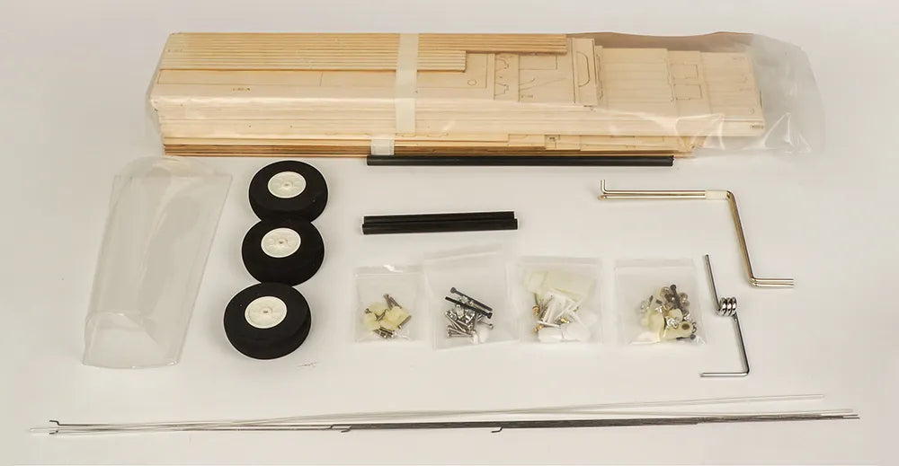 Model kit components including wooden parts, wheels, and tools on a white background